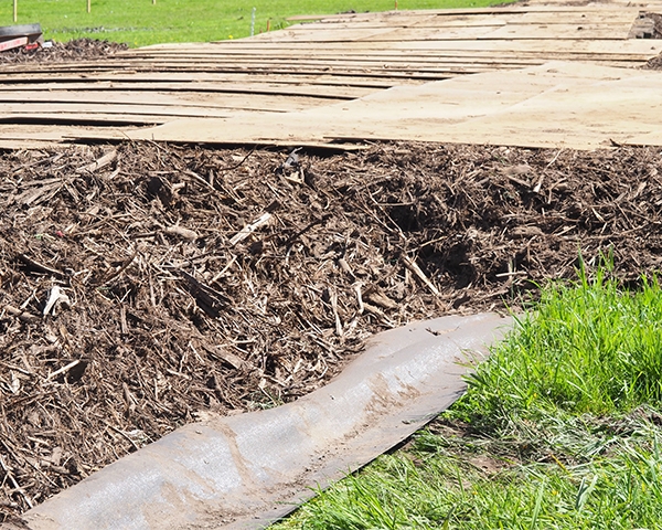 De opbouw van de tijdelijke rijbaan van dichtbij: worteldoek onderop, daarop een laag houtsnippers en daarop de rijplaten